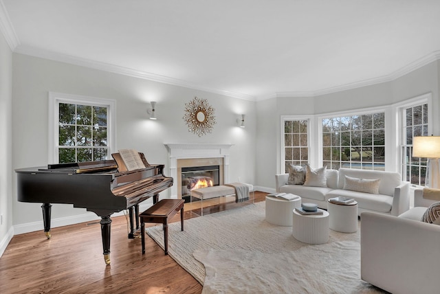 living room with a glass covered fireplace, crown molding, baseboards, and wood finished floors