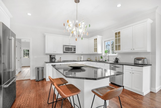 kitchen featuring a breakfast bar area, stainless steel appliances, tasteful backsplash, dark countertops, and crown molding