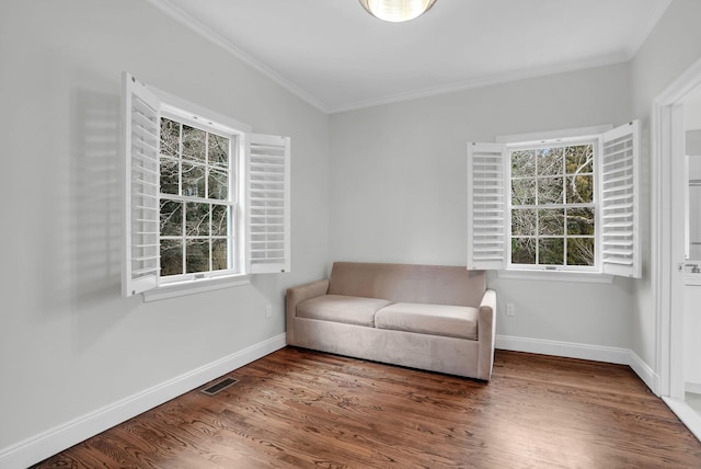 living area featuring crown molding, visible vents, baseboards, and wood finished floors