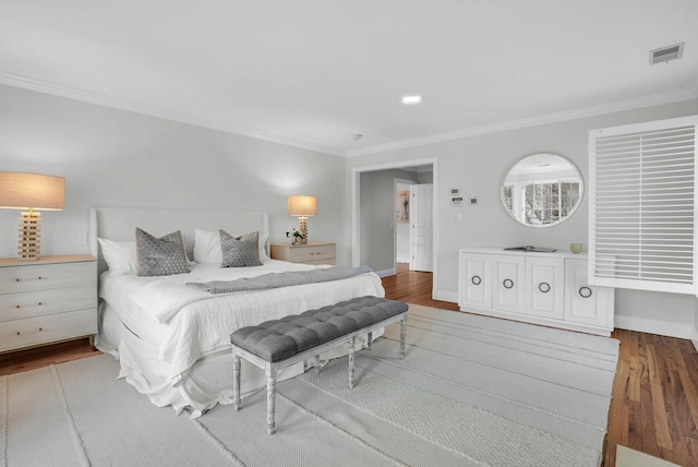 bedroom with ornamental molding, wood finished floors, visible vents, and baseboards