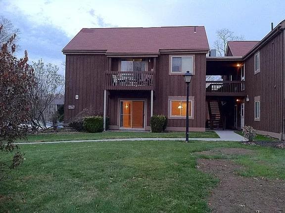 back of property featuring a yard, a balcony, and stairs