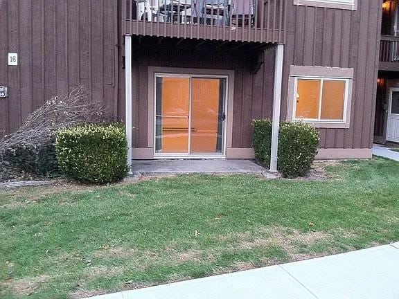 entrance to property featuring board and batten siding, a lawn, and a balcony