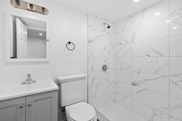 bathroom featuring toilet, tiled shower, and vanity