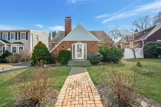 view of front of house with brick siding, a chimney, a front lawn, and fence