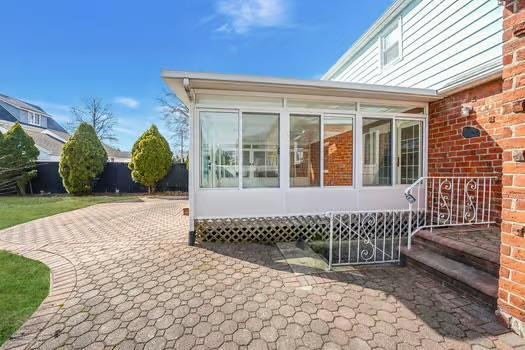 view of home's exterior with a sunroom and brick siding