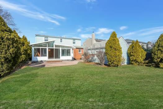 rear view of property featuring a sunroom and a lawn