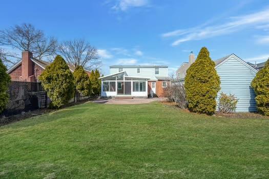 rear view of property with a sunroom, a yard, and fence