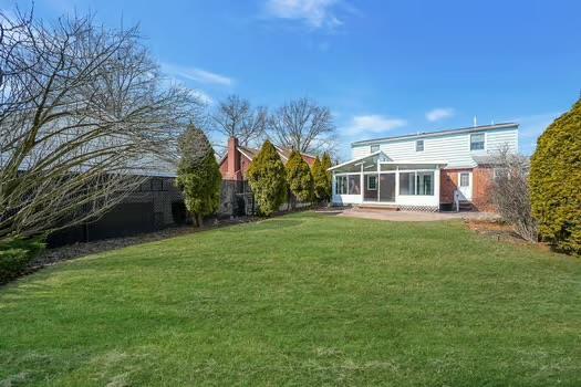 back of house with a sunroom, a patio, and a yard