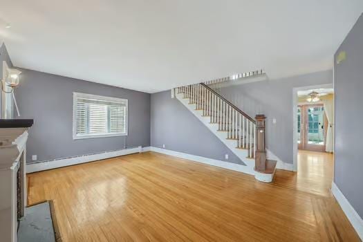 unfurnished living room featuring french doors, a baseboard radiator, stairway, wood finished floors, and baseboards