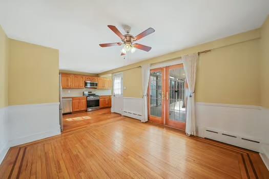 unfurnished living room featuring light wood-style floors, a baseboard heating unit, ceiling fan, and baseboard heating