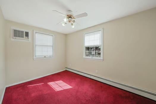 carpeted empty room with ceiling fan, an AC wall unit, a baseboard radiator, and baseboards