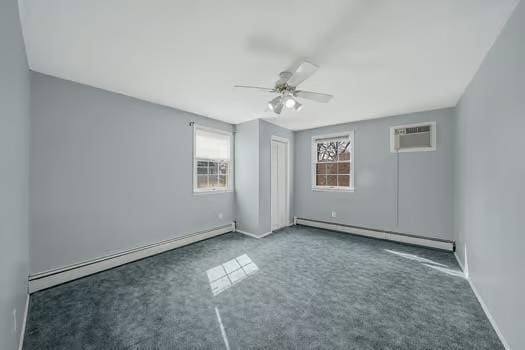 spare room with dark colored carpet, a baseboard radiator, a ceiling fan, and a wall mounted air conditioner