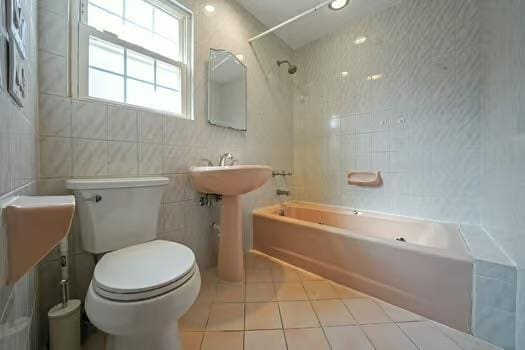 full bath with shower / bathtub combination, toilet, tile patterned flooring, and tile walls