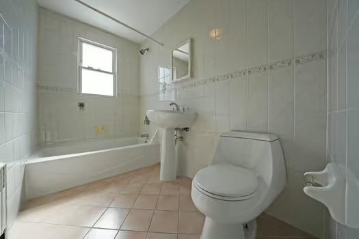 bathroom featuring tile patterned flooring, tub / shower combination, tile walls, and toilet