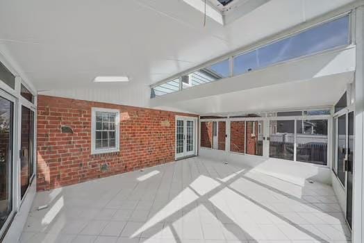 unfurnished sunroom featuring lofted ceiling with skylight