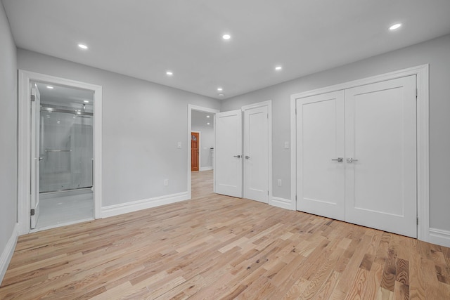 unfurnished bedroom featuring light wood-type flooring, connected bathroom, and recessed lighting