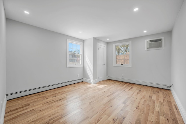 empty room featuring a wall mounted air conditioner, wood finished floors, a baseboard heating unit, and plenty of natural light