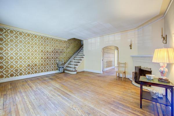 living area with stairs, a fireplace, wood finished floors, baseboards, and wallpapered walls