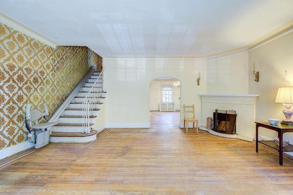 living room with wallpapered walls, a brick fireplace, arched walkways, and light wood finished floors