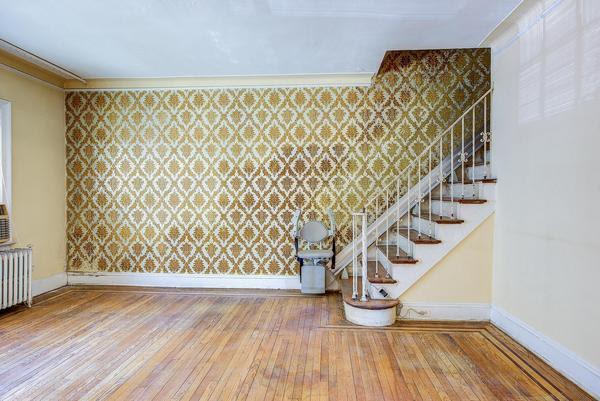 empty room featuring baseboards, radiator, wood finished floors, stairs, and crown molding