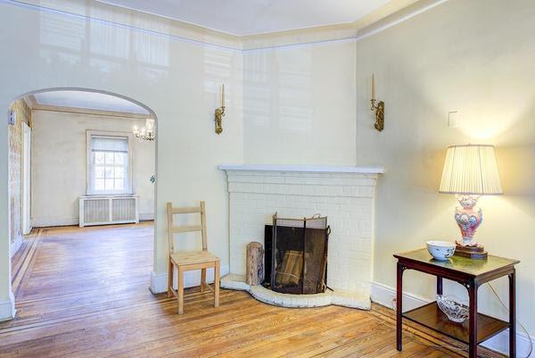 living room featuring baseboards, arched walkways, radiator heating unit, wood finished floors, and a fireplace