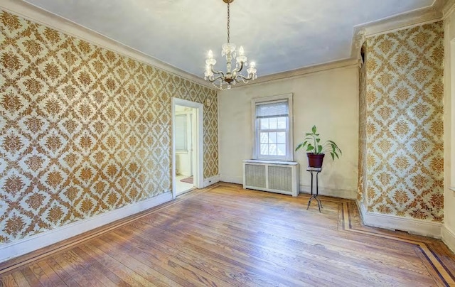 empty room with radiator heating unit, ornamental molding, light wood-style floors, baseboards, and wallpapered walls