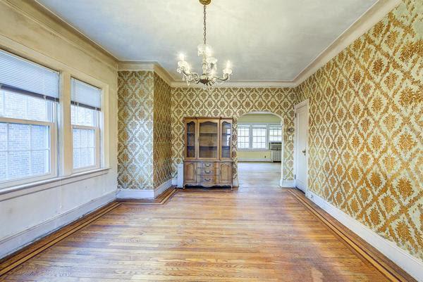 spare room featuring ornamental molding, wood finished floors, baseboards, and wallpapered walls