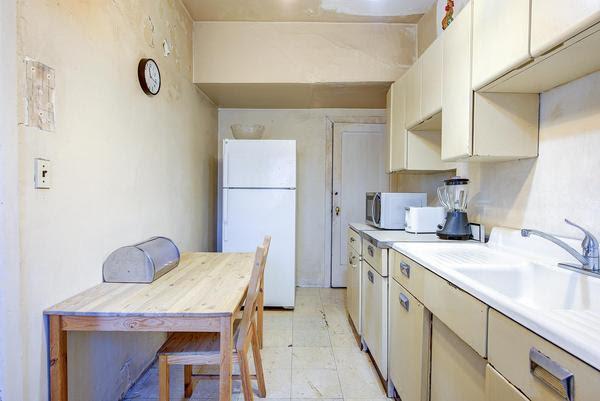 kitchen with light countertops, stainless steel microwave, a sink, and freestanding refrigerator