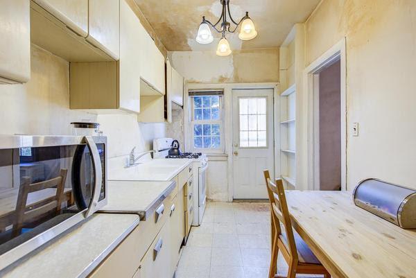 kitchen with a notable chandelier, light countertops, stainless steel microwave, hanging light fixtures, and white range with gas cooktop