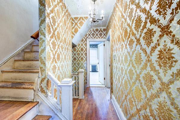 stairs featuring wallpapered walls, baseboards, wood finished floors, crown molding, and a chandelier