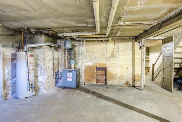 unfinished basement featuring water heater and stairway