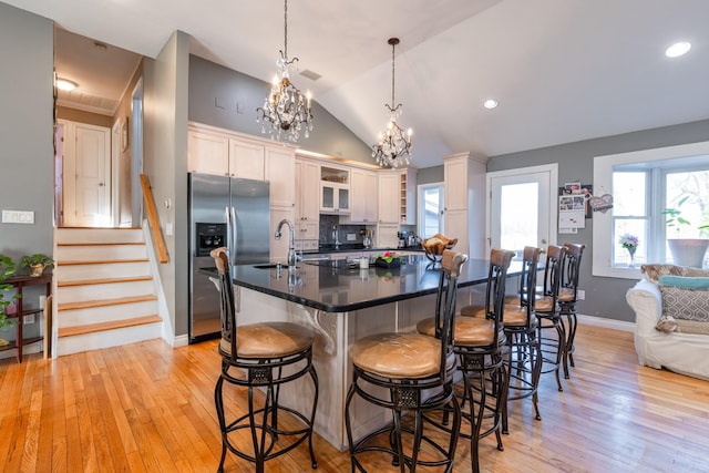 kitchen featuring pendant lighting, tasteful backsplash, dark countertops, stainless steel fridge with ice dispenser, and a kitchen breakfast bar