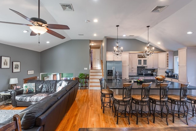 kitchen featuring visible vents, dark countertops, decorative light fixtures, a kitchen bar, and stainless steel refrigerator with ice dispenser