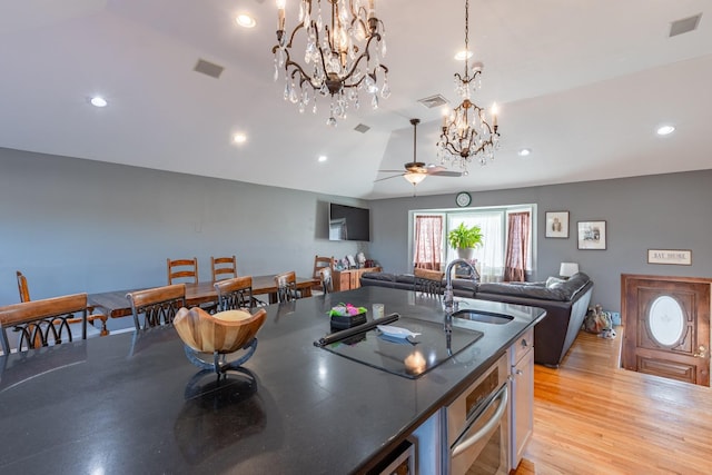 kitchen featuring dark countertops, open floor plan, black electric cooktop, stainless steel oven, and a sink