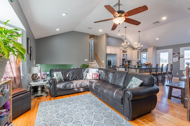 living room with light wood-type flooring, visible vents, lofted ceiling, and stairs