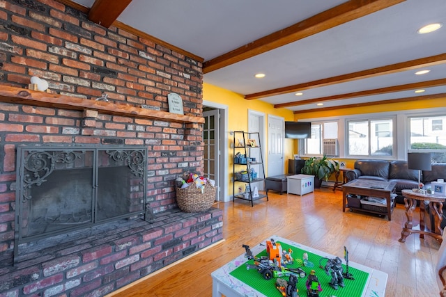 living room with a fireplace, beamed ceiling, and hardwood / wood-style flooring