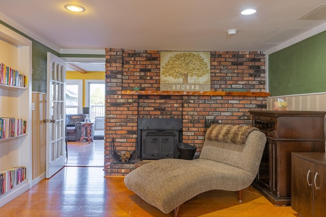 sitting room featuring ornamental molding, light wood-type flooring, a wood stove, and recessed lighting