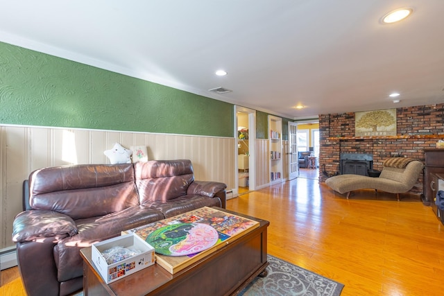 living room featuring recessed lighting, visible vents, a textured wall, wainscoting, and wood finished floors