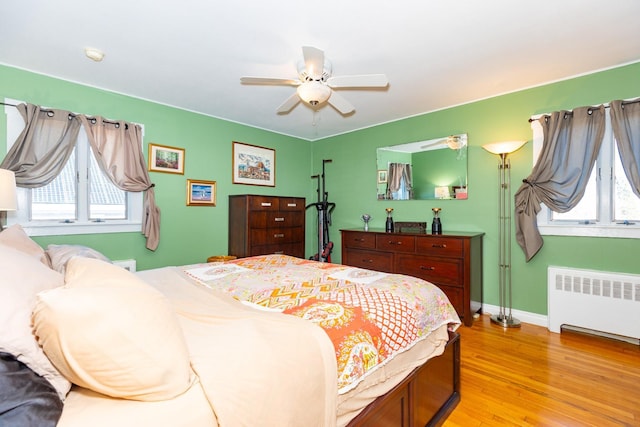 bedroom featuring baseboards, ceiling fan, light wood-style floors, and radiator