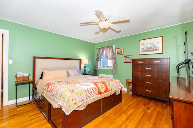 bedroom featuring a ceiling fan, radiator, baseboards, and light wood finished floors