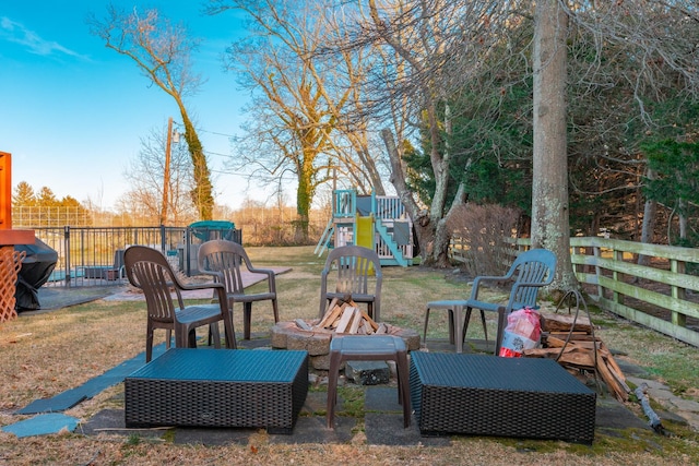 view of yard featuring an outdoor fire pit, a playground, and fence