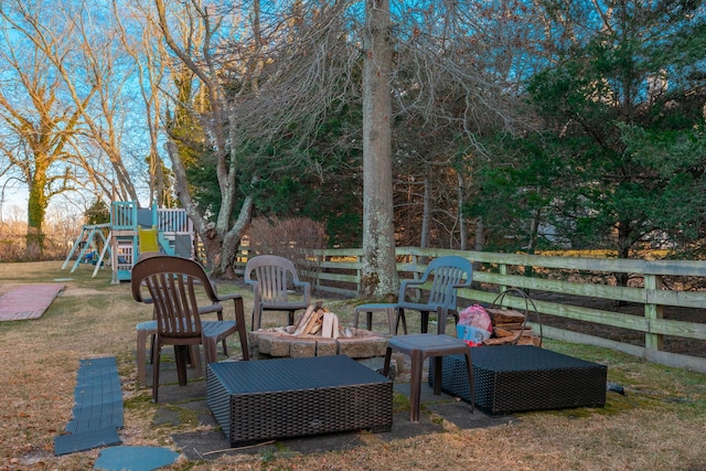 view of patio with an outdoor fire pit, a playground, and fence