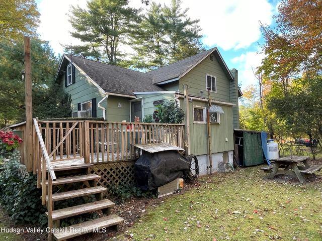 rear view of property featuring a deck, a lawn, and stairs