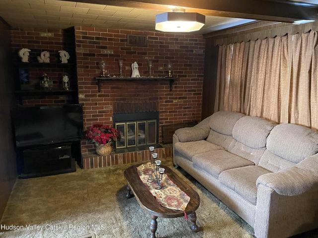 living area featuring carpet flooring, a fireplace, and visible vents