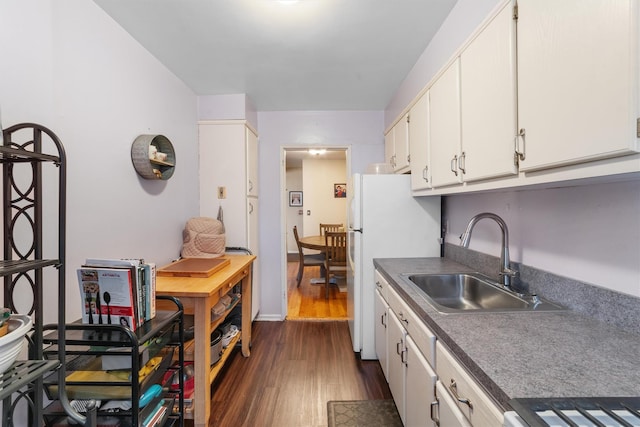 kitchen featuring dark wood finished floors, white cabinets, a sink, and freestanding refrigerator