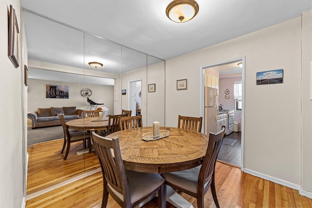 dining space featuring light wood-type flooring and baseboards