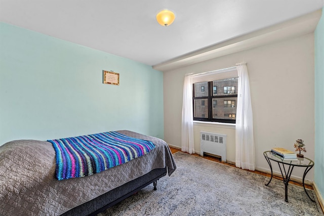 bedroom featuring radiator, baseboards, and wood finished floors