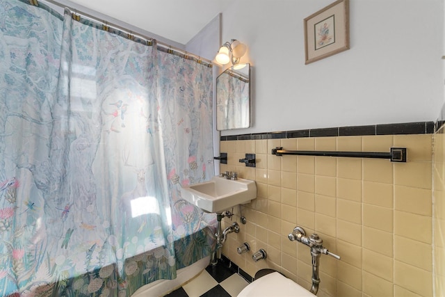 full bathroom with a sink, toilet, tile walls, and wainscoting