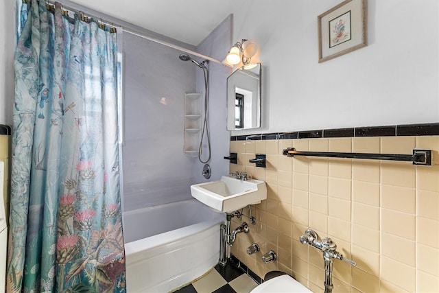 bathroom featuring a sink, shower / bath combo, tile walls, and wainscoting