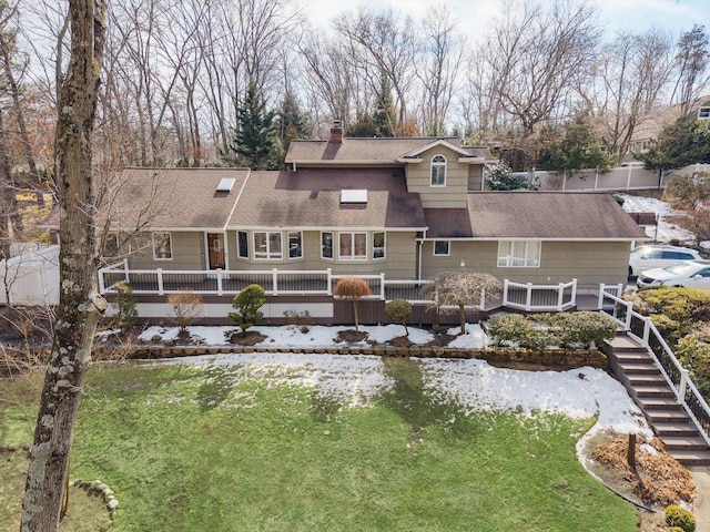 back of property with a chimney, stairway, roof with shingles, fence, and a yard